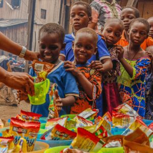Joyful children receiving food supplies from a volunteer in an outdoor setting.